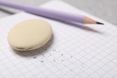 Photo of Eraser, pencil, scraps and notebook on table, closeup