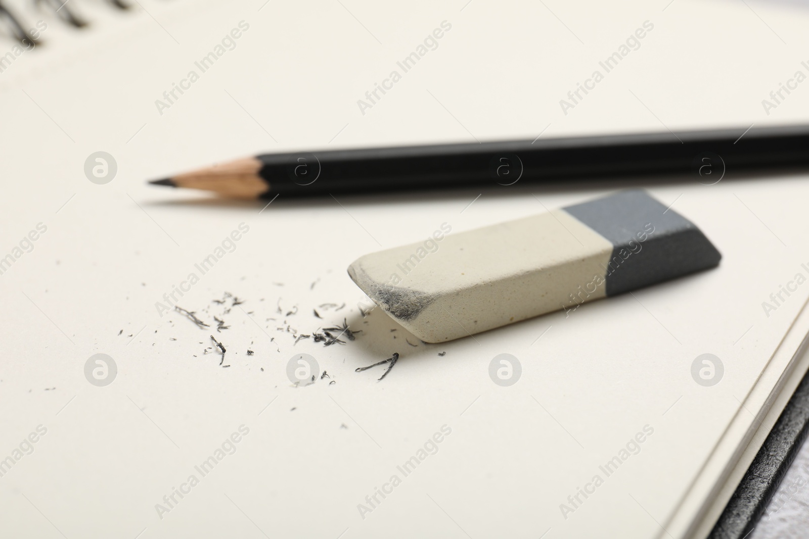 Photo of Eraser, pencil and scraps on notebook, closeup