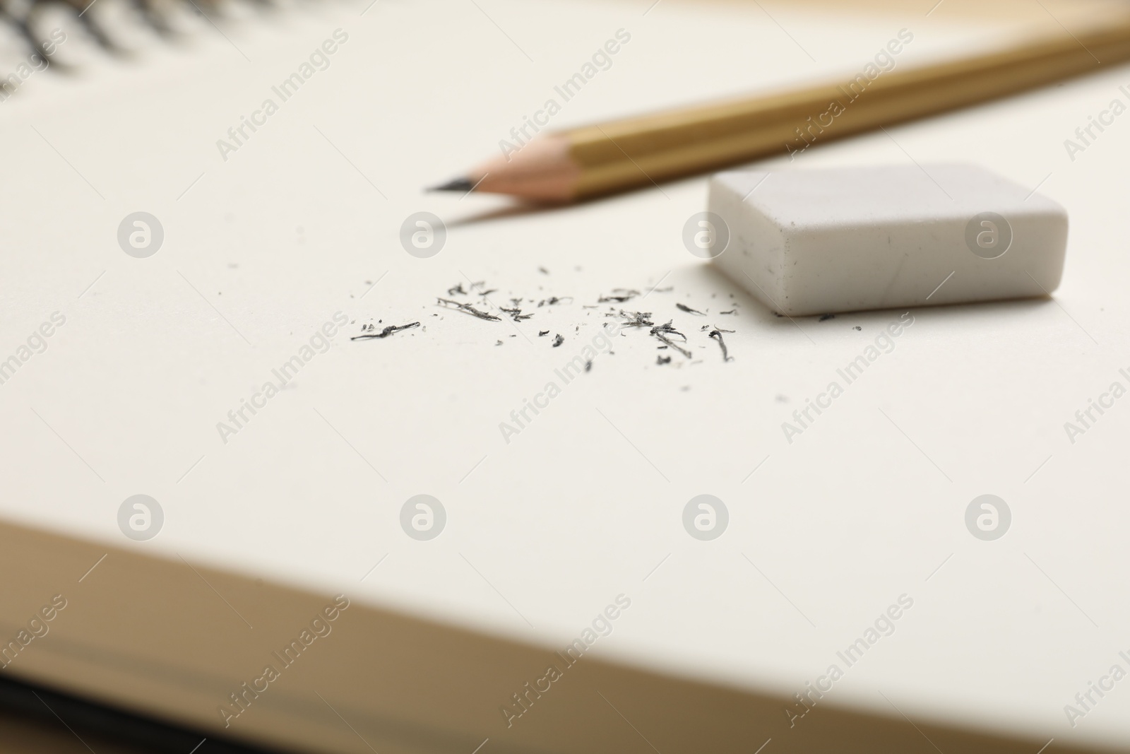 Photo of Eraser, pencil and scraps on notebook, closeup