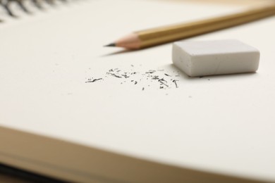 Photo of Eraser, pencil and scraps on notebook, closeup