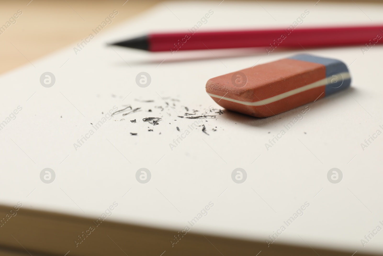 Photo of Eraser, pencil and scraps on notebook, closeup