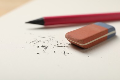 Photo of Eraser, pencil and scraps on notebook, closeup