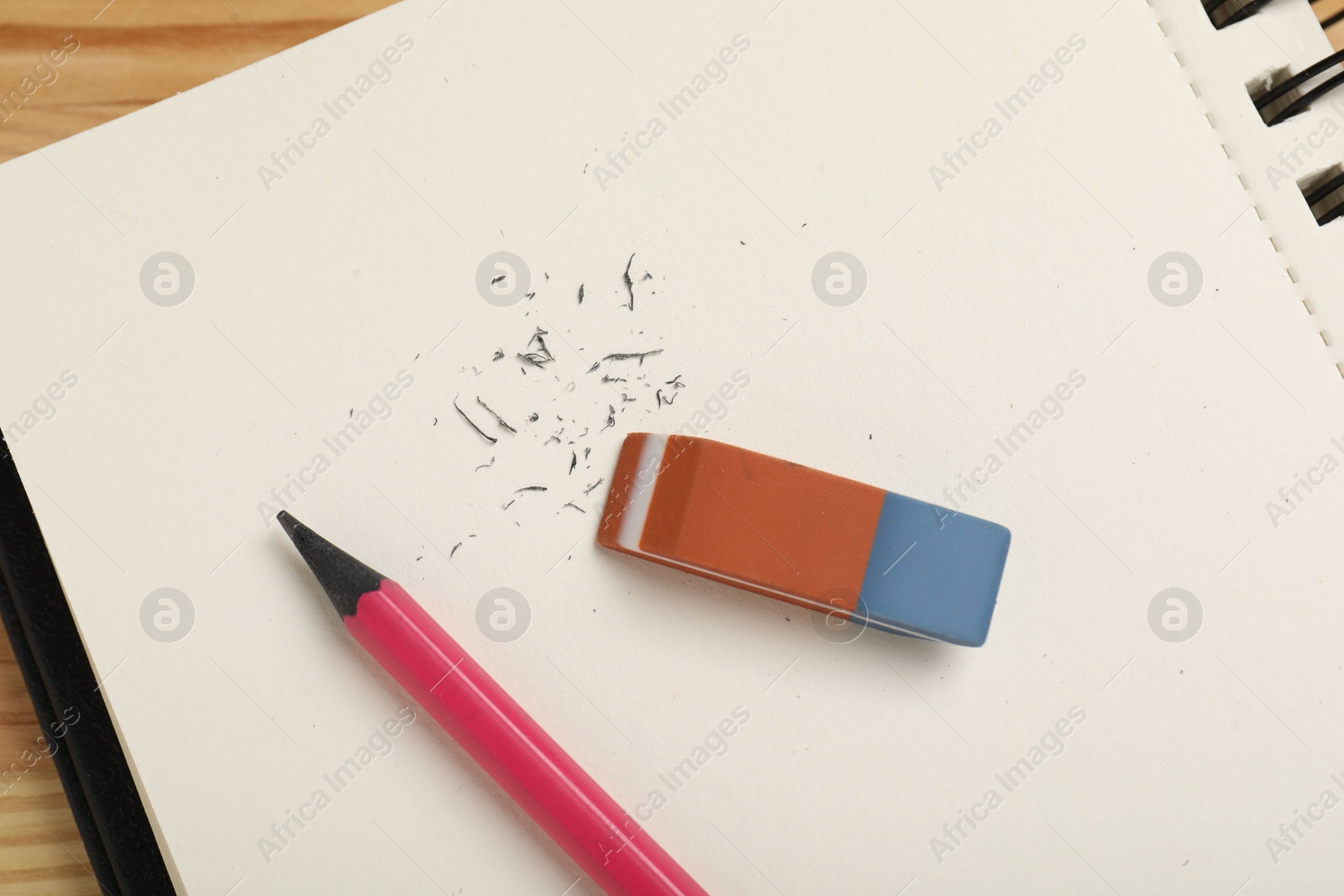 Photo of Eraser, pencil, scraps and notebook on table, top view