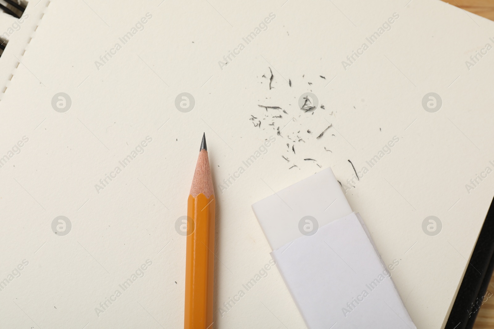 Photo of Eraser, pencil, scraps and notebook on table, top view