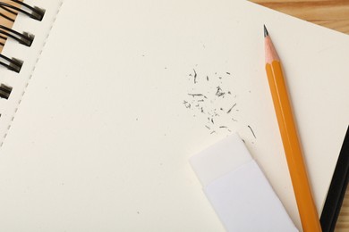 Photo of Eraser, pencil, scraps and notebook on table, top view