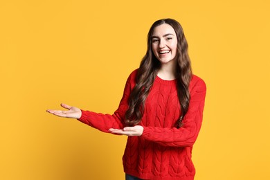 Photo of Happy woman welcoming friends or guests on yellow background