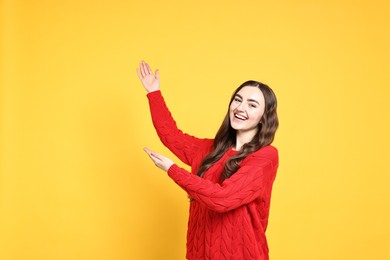 Photo of Happy woman welcoming friends or guests on yellow background