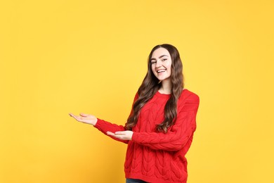 Photo of Happy woman welcoming friends or guests on yellow background