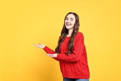 Happy woman welcoming friends or guests on yellow background