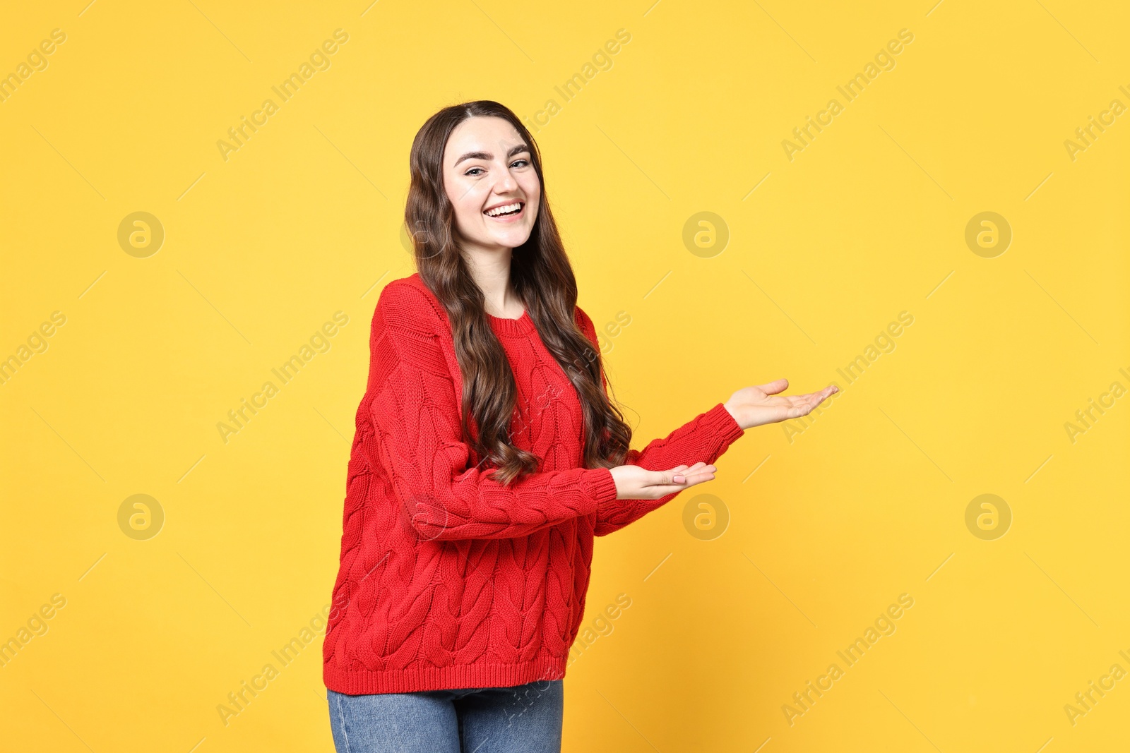 Photo of Happy woman welcoming friends or guests on yellow background