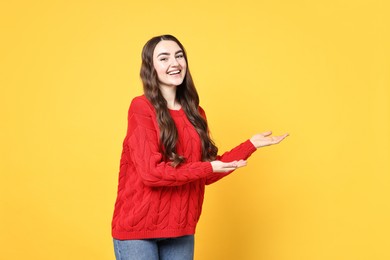 Happy woman welcoming friends or guests on yellow background