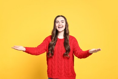 Photo of Happy woman welcoming friends or guests on yellow background