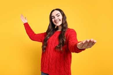 Photo of Happy woman welcoming friends or guests on yellow background, low angle view