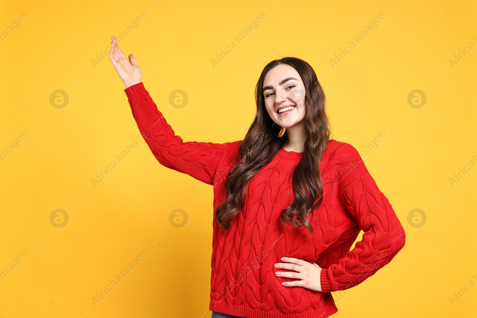 Photo of Happy woman welcoming friends or guests on yellow background