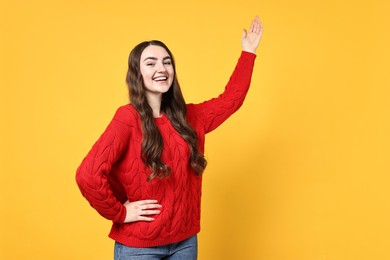 Photo of Happy woman welcoming friends or guests on yellow background