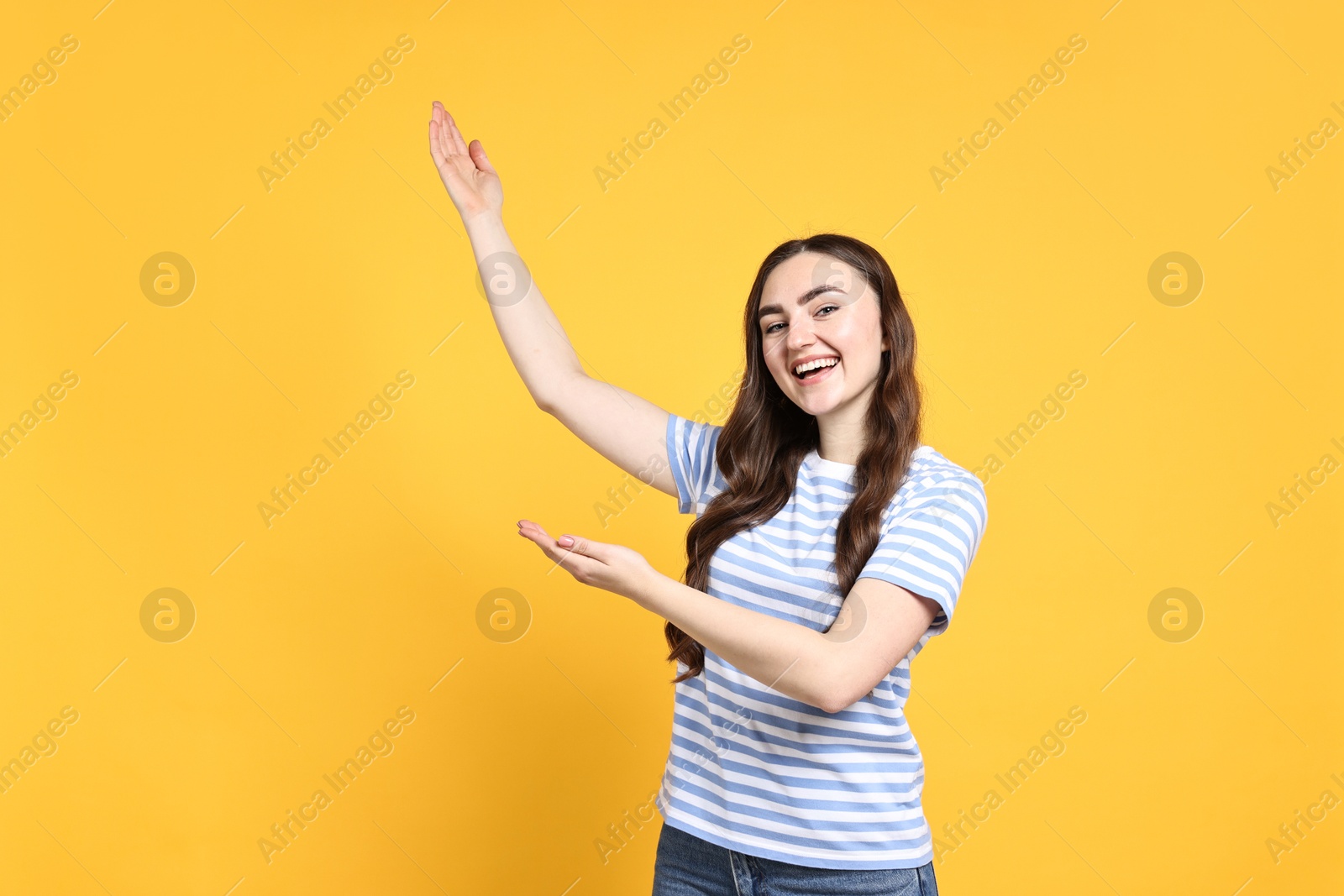 Photo of Happy woman welcoming friends or guests on yellow background