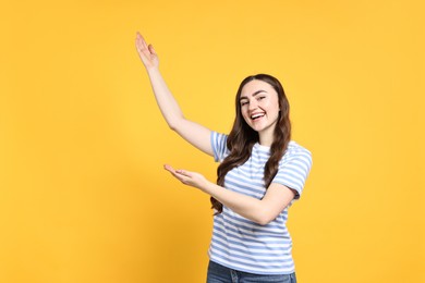 Happy woman welcoming friends or guests on yellow background