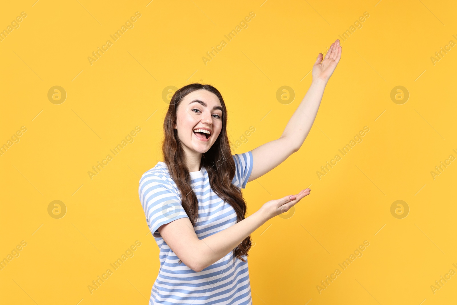 Photo of Happy woman welcoming friends or guests on yellow background