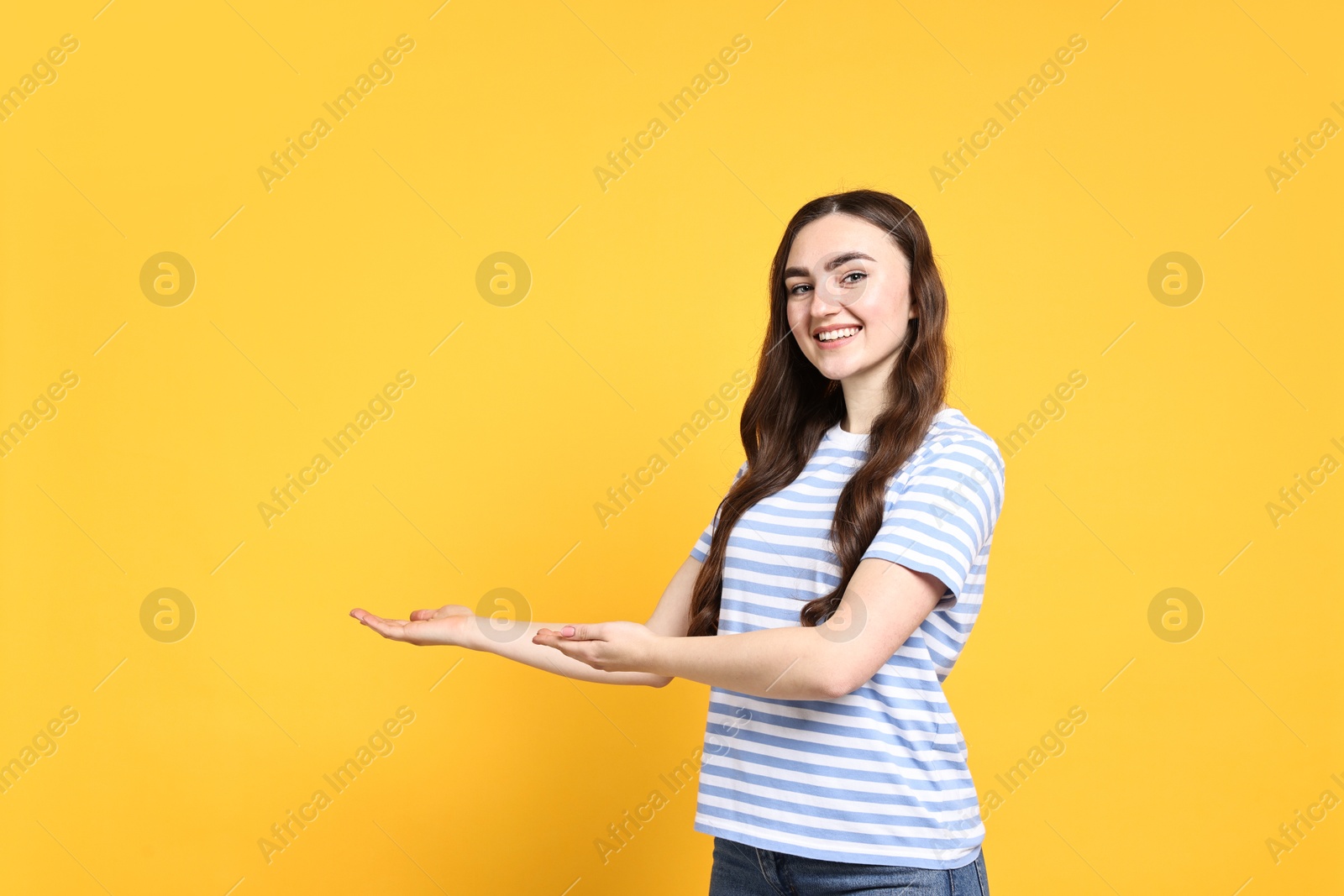 Photo of Happy woman welcoming friends or guests on yellow background