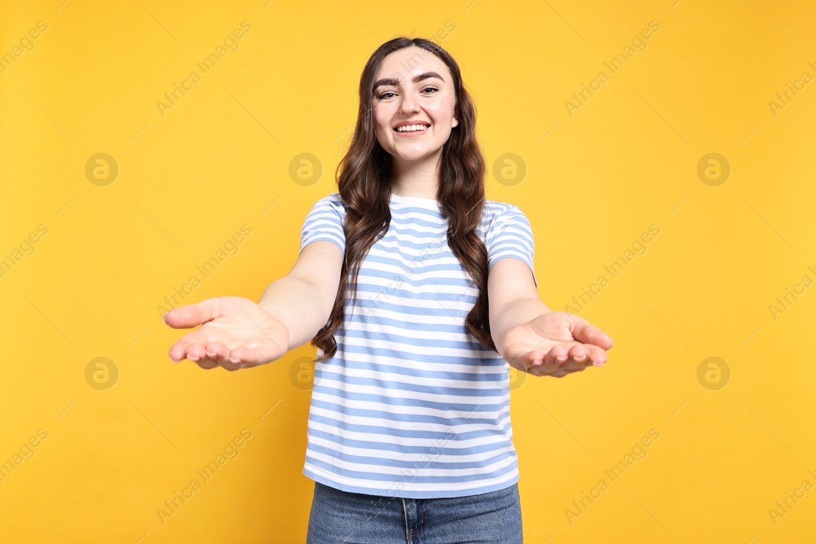 Photo of Happy woman welcoming friends or guests on yellow background, low angle view