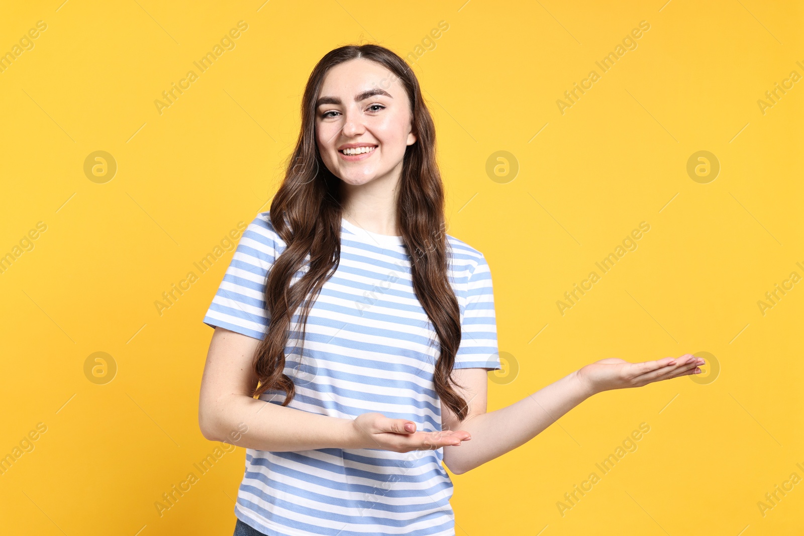 Photo of Happy woman welcoming friends or guests on yellow background