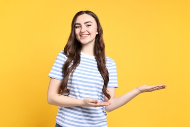 Photo of Happy woman welcoming friends or guests on yellow background