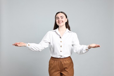 Photo of Happy businesswoman welcoming clients or partners with wide open arms on grey background