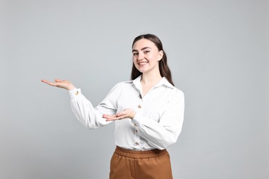 Photo of Happy businesswoman welcoming clients or partners on grey background