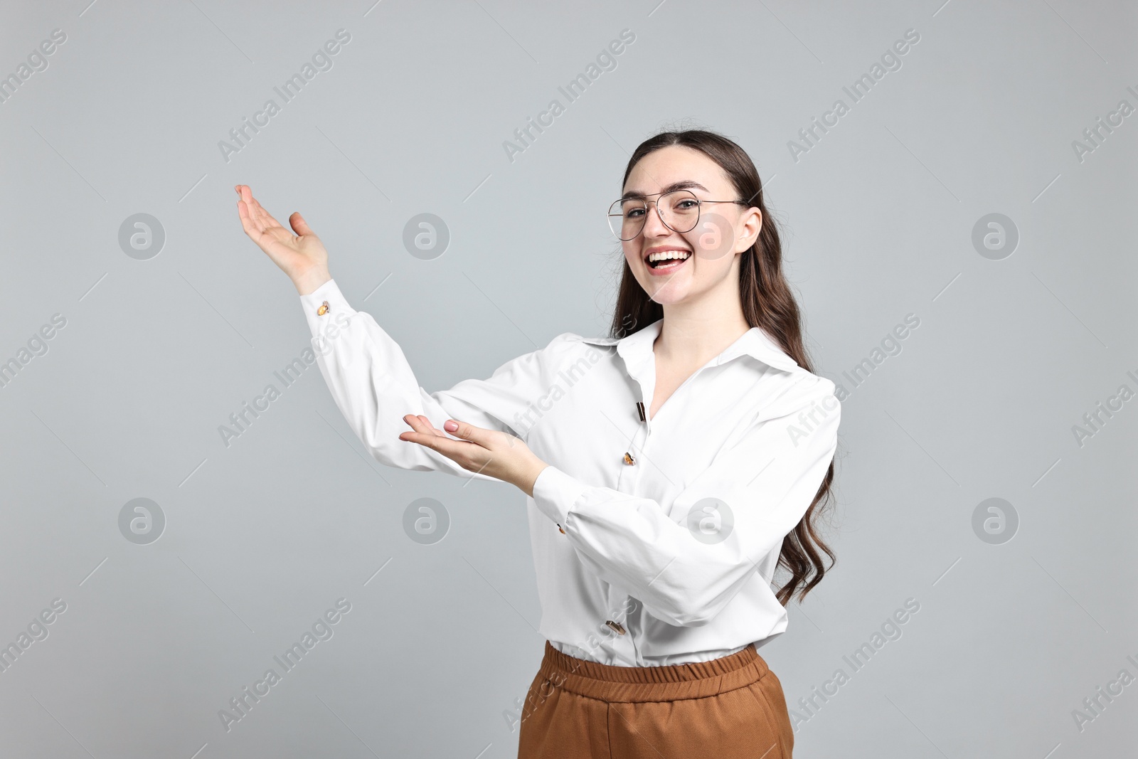 Photo of Happy businesswoman welcoming clients or partners on grey background