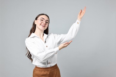 Photo of Happy businesswoman welcoming clients or partners on grey background