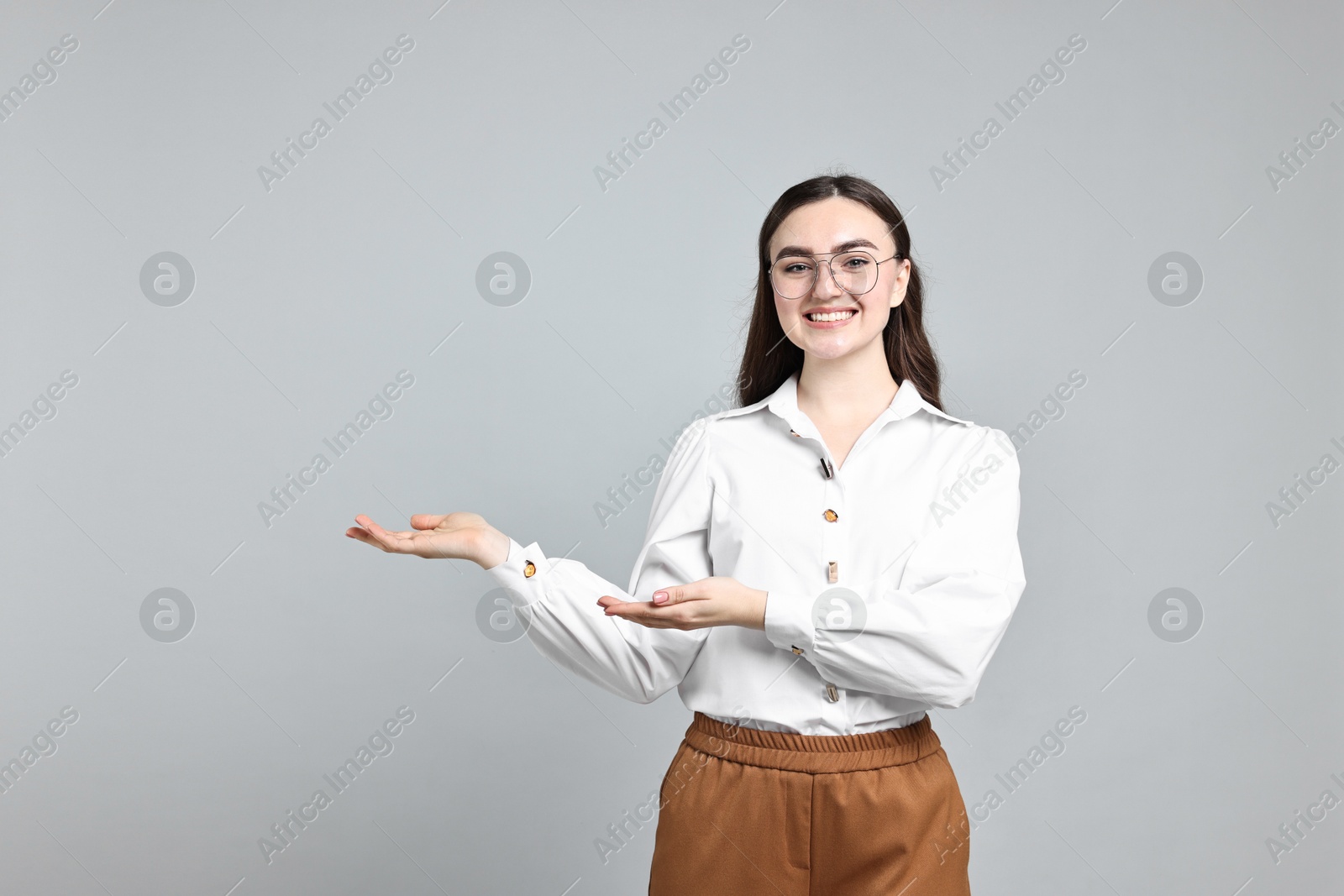 Photo of Happy businesswoman welcoming clients or partners on grey background. Space for text