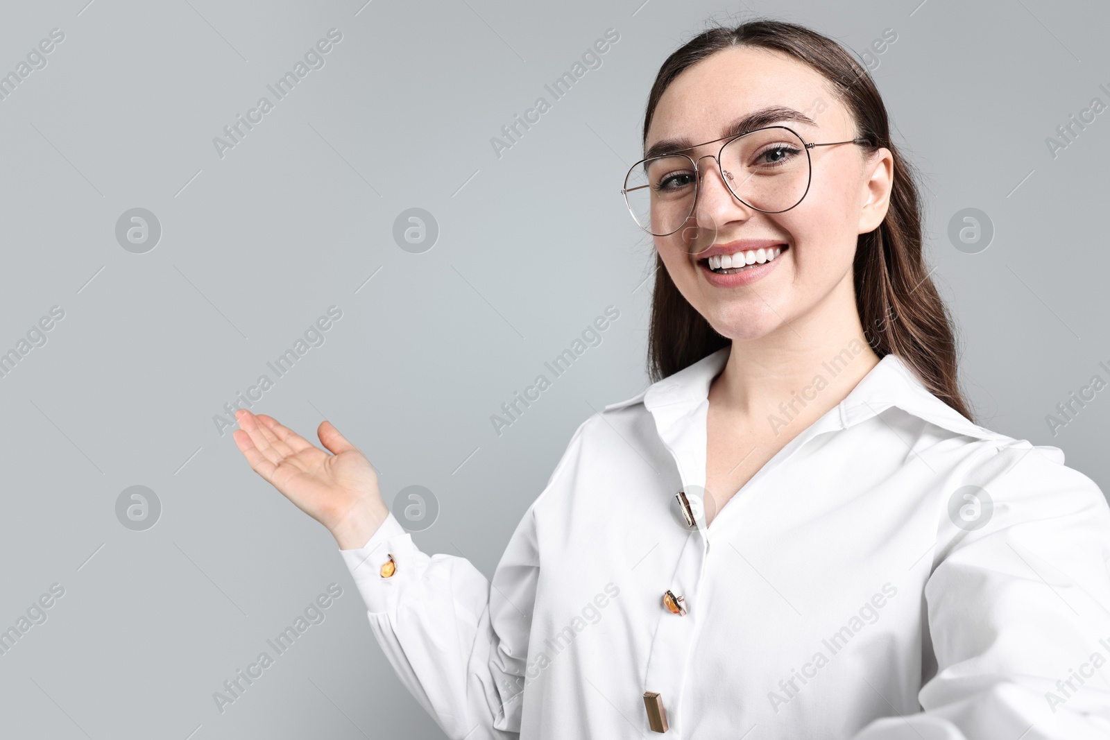 Photo of Happy businesswoman taking selfie and welcoming clients or partners on grey background. Space for text