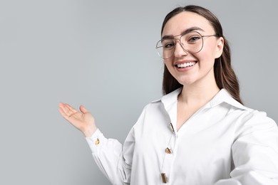 Photo of Happy businesswoman taking selfie and welcoming clients or partners on grey background. Space for text