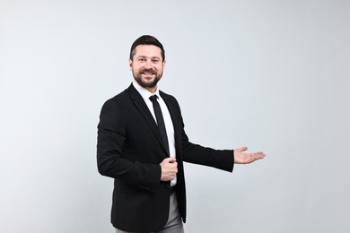 Photo of Happy businessman welcoming clients or partners on grey background