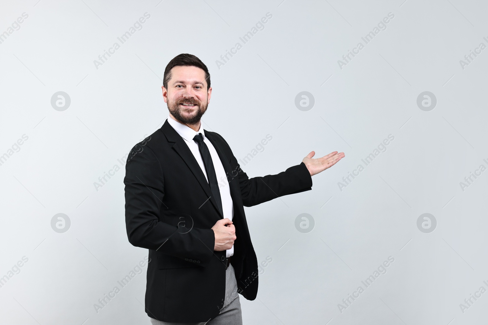 Photo of Happy businessman welcoming clients or partners on grey background