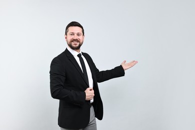 Photo of Happy businessman welcoming clients or partners on grey background