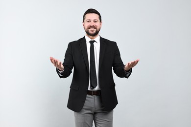 Happy businessman welcoming clients or partners on grey background