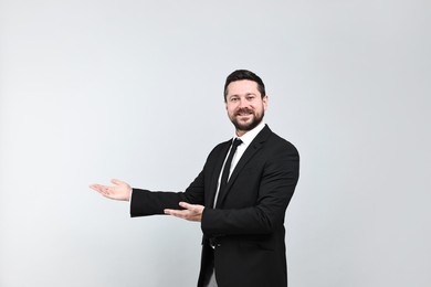 Photo of Happy businessman welcoming clients or partners on grey background