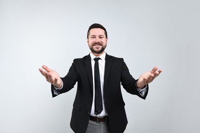 Photo of Happy businessman welcoming clients or partners on grey background