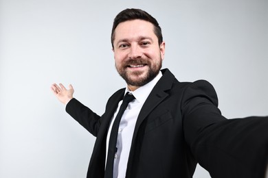 Photo of Happy businessman welcoming clients or partners on grey background, view through front camera of gadget