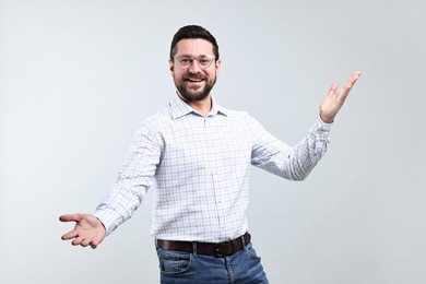 Photo of Happy man welcoming friends or guests on grey background