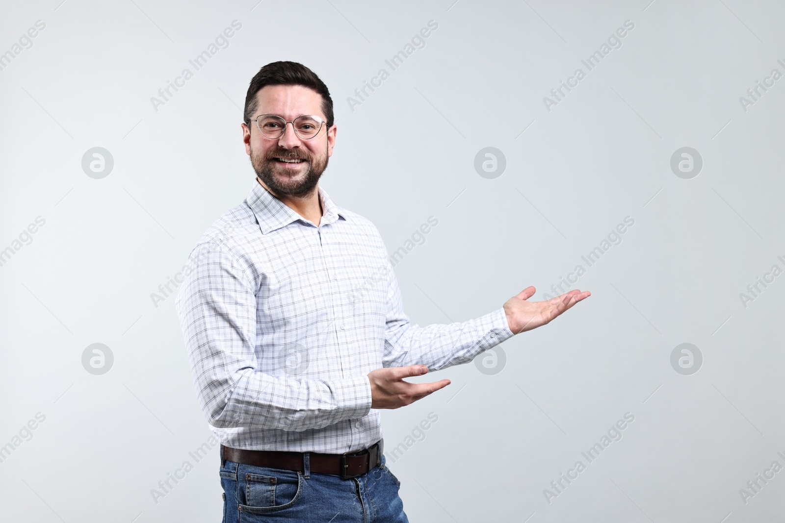 Photo of Happy man welcoming friends or guests on grey background