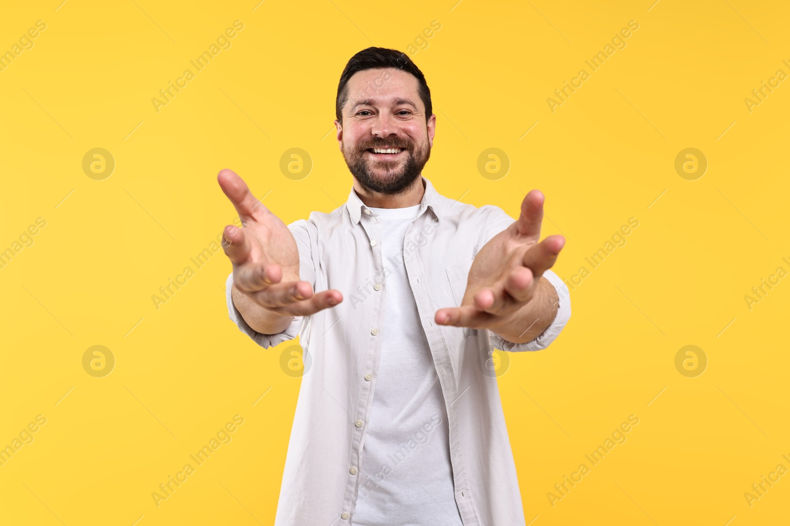 Photo of Happy man welcoming friends or guests on yellow background, low angle view