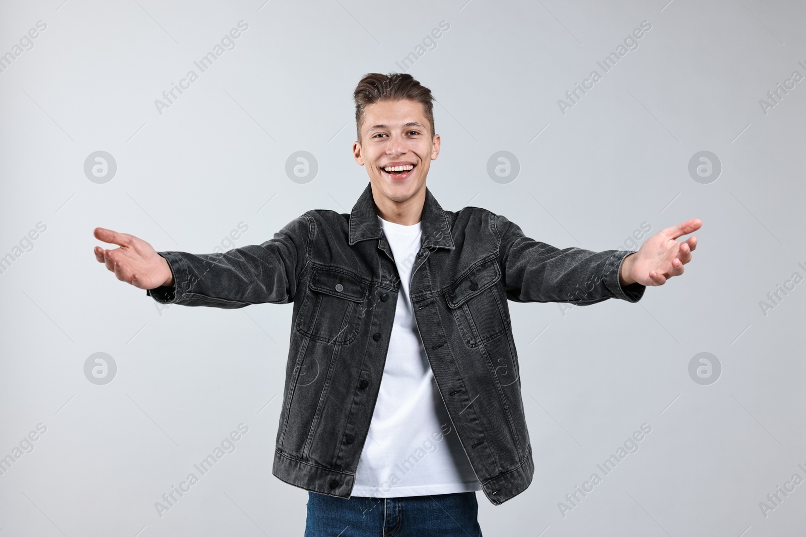 Photo of Happy man welcoming friends or guests on grey background