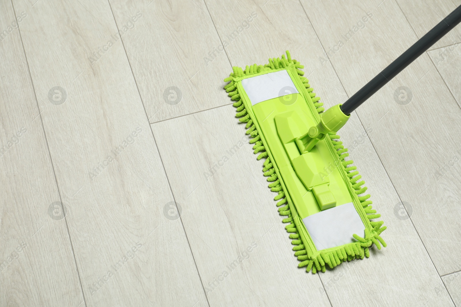 Photo of Microfiber mop on wooden floor, space for text