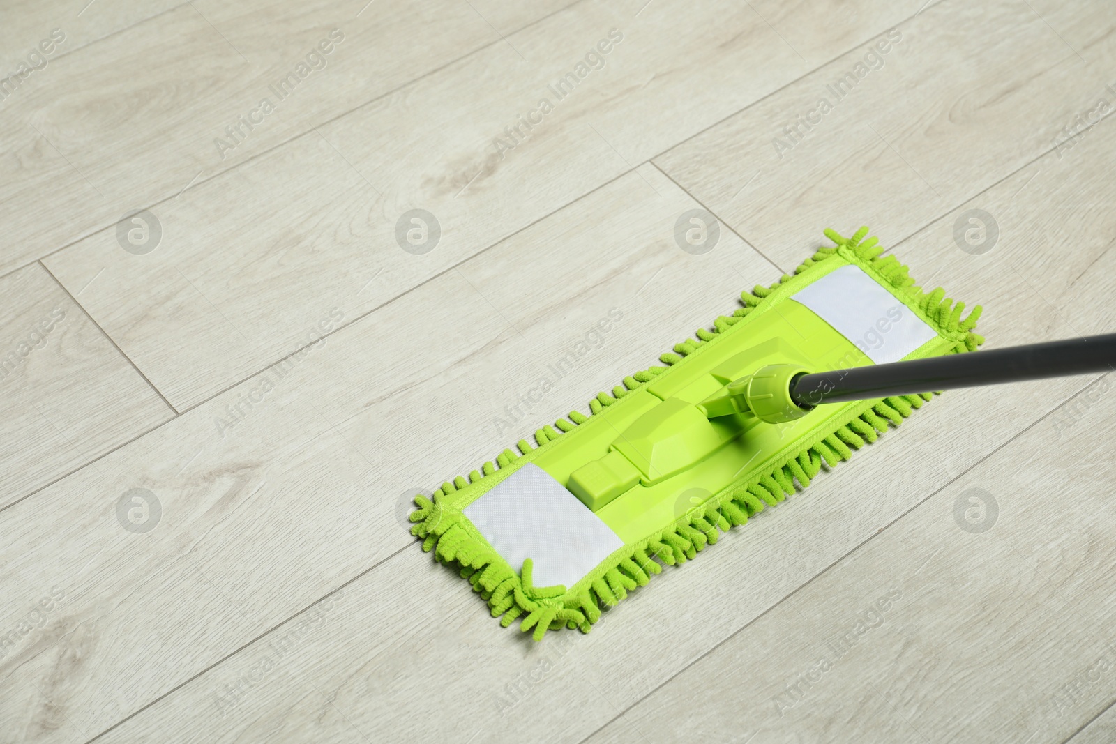 Photo of Microfiber mop on wooden floor, space for text