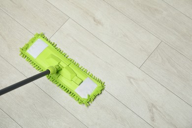 Photo of Microfiber mop on wooden floor, top view. Space for text