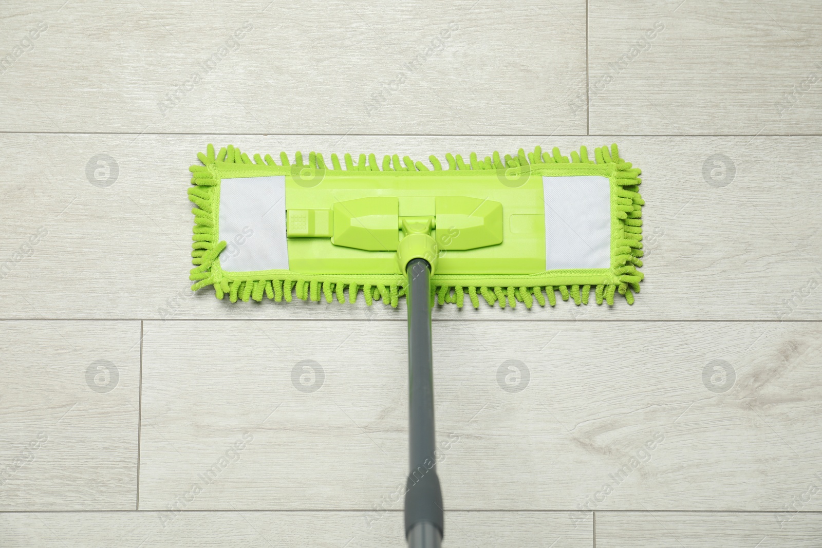 Photo of Microfiber mop on wooden floor, top view