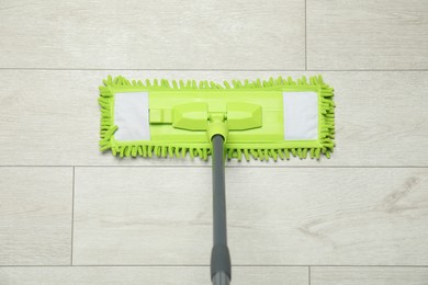 Microfiber mop on wooden floor, top view