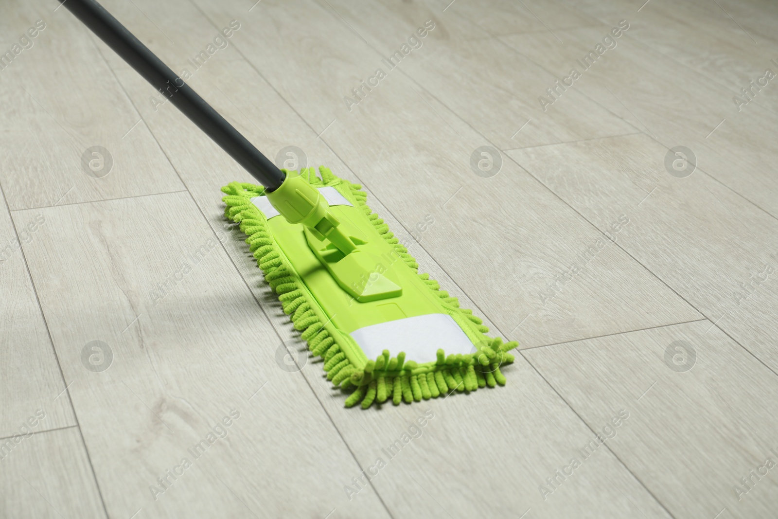 Photo of Microfiber mop on wooden floor, space for text